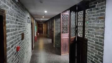 Un pasillo con paredes de ladrillo, puertas de madera y suelo de baldosas.