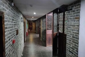 A corridor with brick walls, wooden doors, and tiled flooring. - Huangyao Bandao Hotel (Zhaoping)