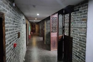 Un pasillo con paredes de ladrillo, puertas de madera y suelo de baldosas.