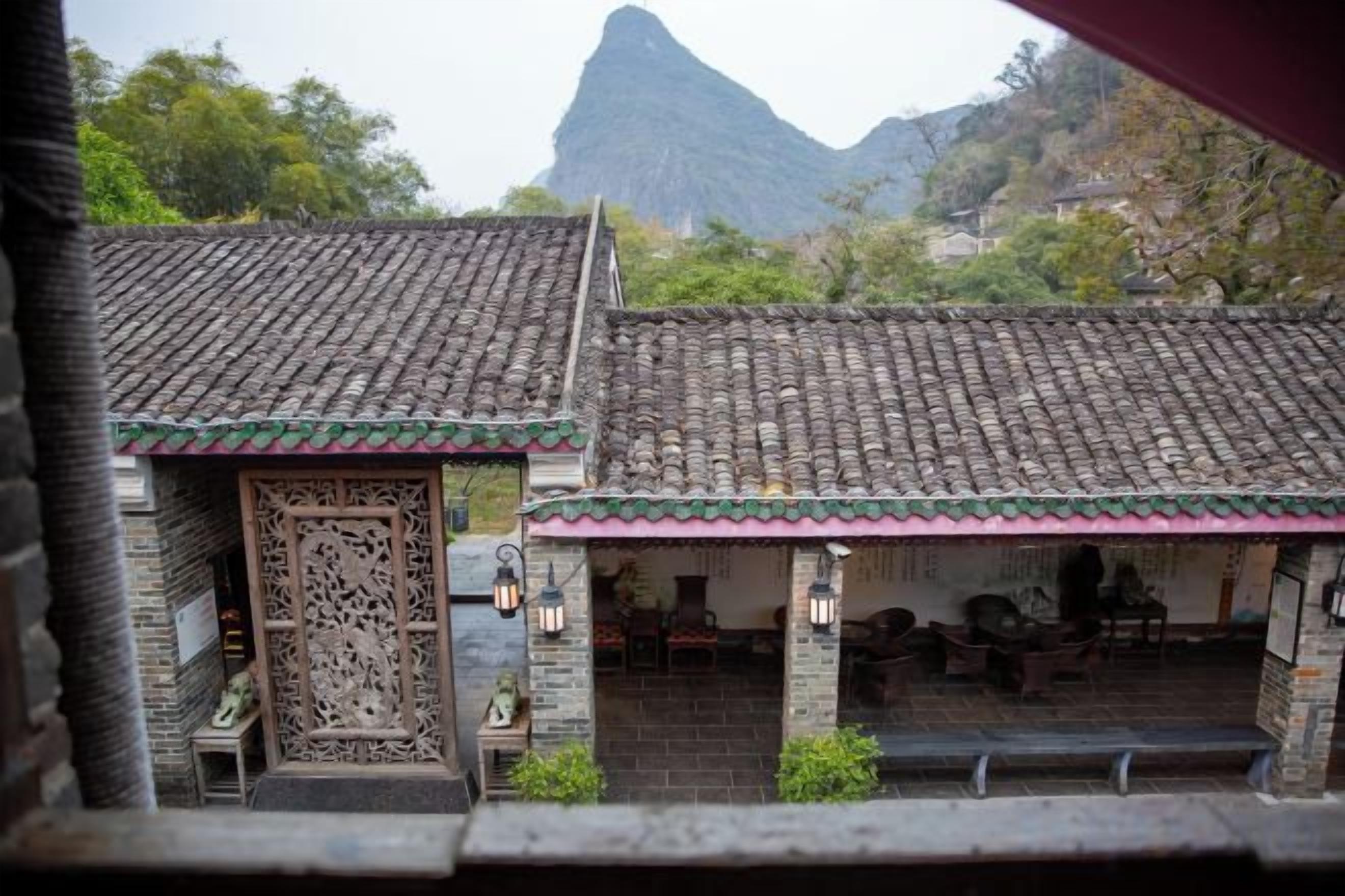Un edificio tradicional con tejado de tejas, un acceso decorativo y una zona de estar con mesas y sillas.