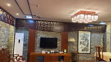 A room with a brick wall, a flat-screen TV, a wooden table, and a sofa.