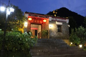 A traditional building with a red entrance, brick walls, and a small staircase leading up to the door. - Huangyao Bandao Hotel (Zhaoping)