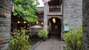 A courtyard with a brick building, a wooden table, and potted plants.