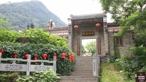 Une porte chinoise traditionnelle, avec un escalier en pierre menant à un bâtiment surmonté d’un toit en tuiles.