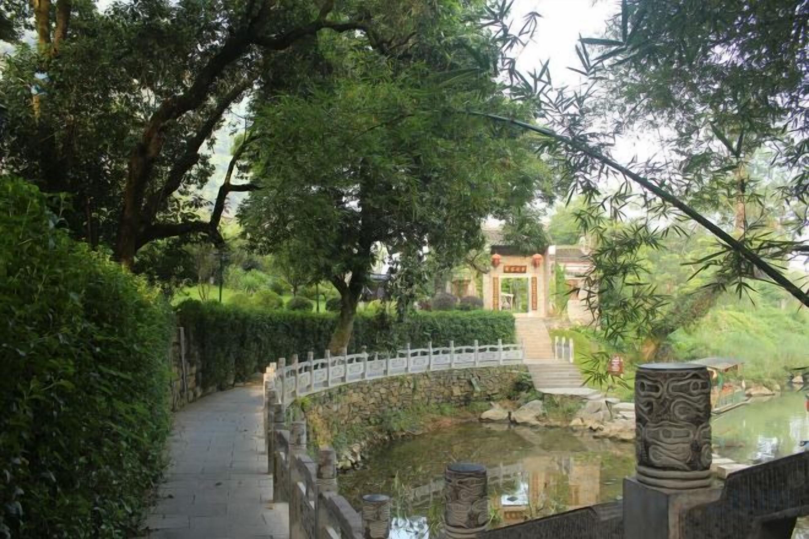 Un camino que lleva a una construcción tradicional con un estanque y un puente.