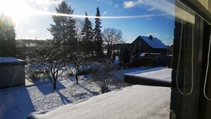 Un paysage enneigé avec une maison et des arbres en arrière-plan.