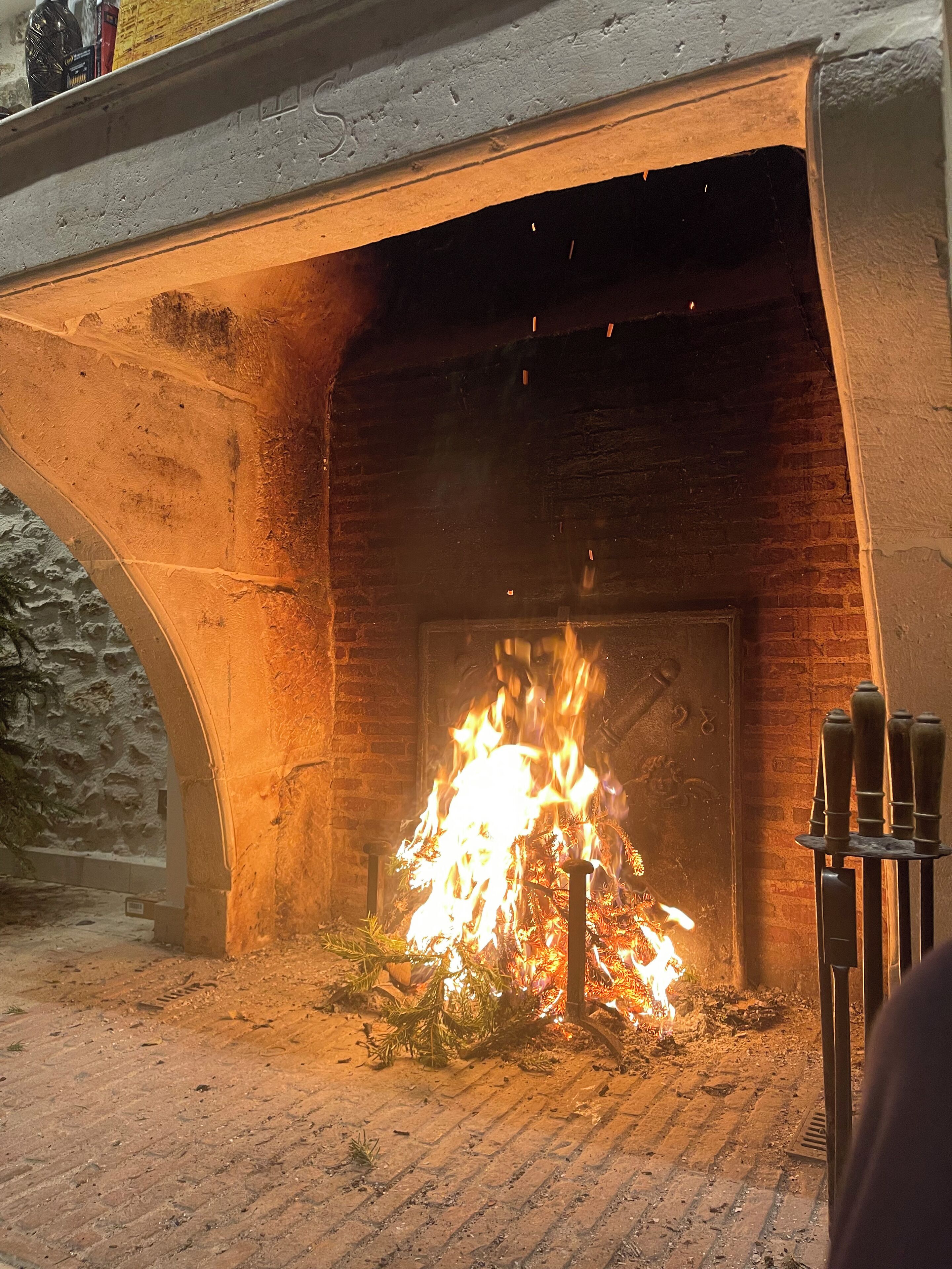 A fireplace with a fire burning inside, set in a stone archway.