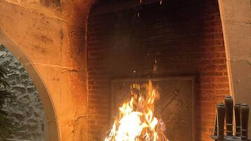A fireplace with a fire burning inside, set in a stone archway.