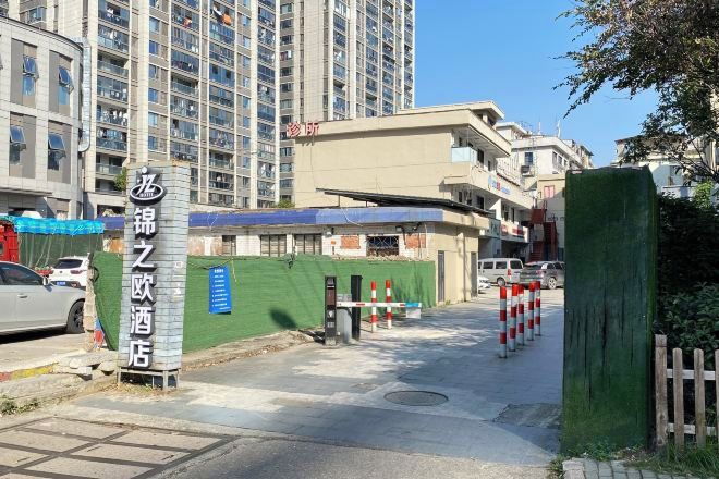 A hotel entrance with a sign, a gated area, and a building in the background.