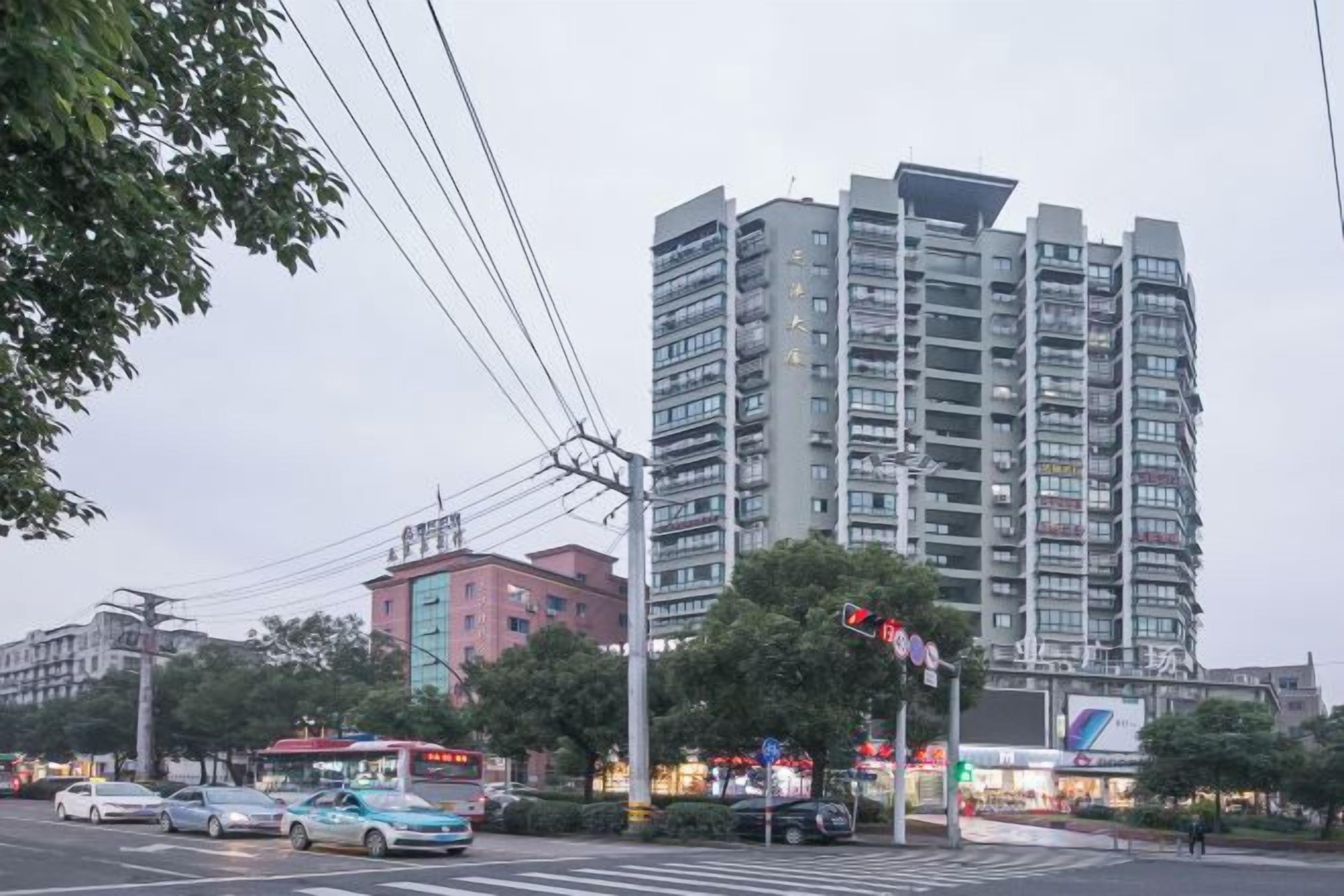 Un edificio de varios pisos con un diseño arquitectónico moderno, situado en un entorno urbano con calle y tráfico visibles.