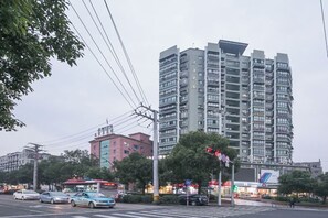A multi-story building with a modern architectural design, located in an urban setting with visible street and traffic. - Jinjiang Inn Select (Wenzhou High-speed Railway Station Xinqiao) (Wenzhou)