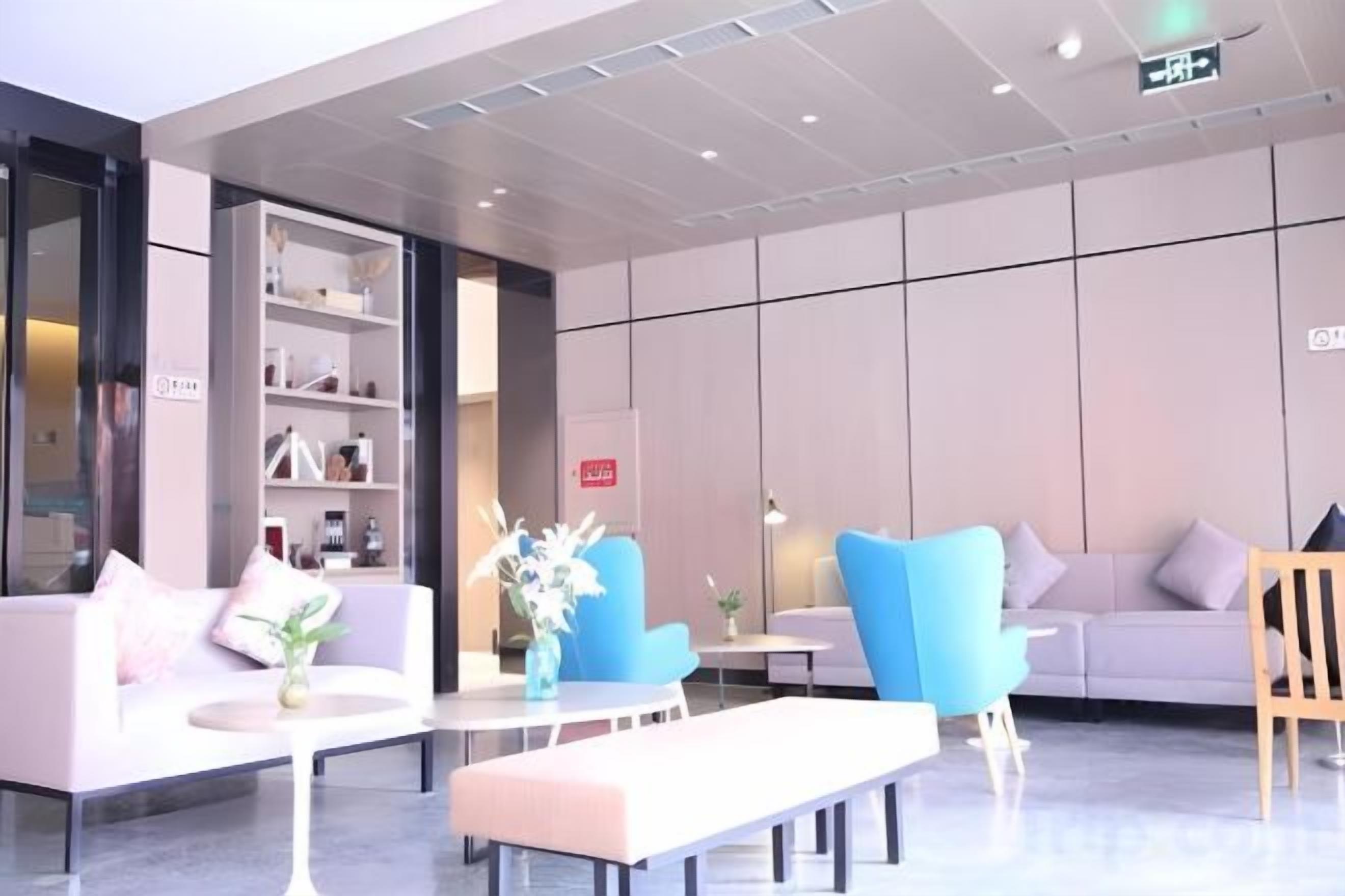 A modern lobby with seating areas, a reception desk, and a bookshelf.
