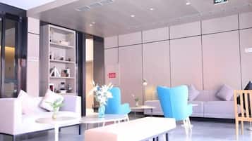 A modern lobby with seating areas, a reception desk, and a bookshelf.