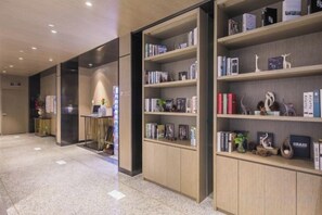A library with bookshelves, a reception area, and a polished floor. - Jinjiang Inn Select (Wenzhou High-speed Railway Station Xinqiao) (Wenzhou)