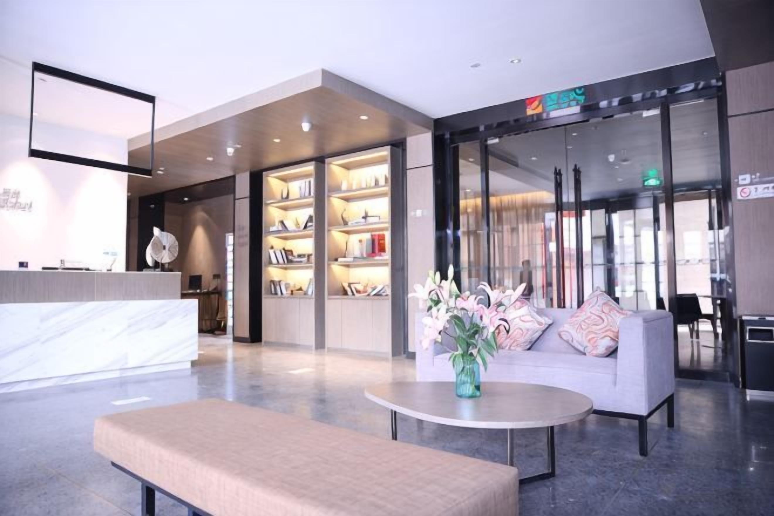 Eine moderne Hotellobby mit einer Rezeption, einer Sitzecke und einem Bücherregal.