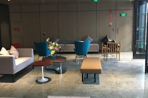 A lobby with seating arrangements, a sofa, a coffee table, and a small table with flowers. - Jinjiang Inn Select (Wenzhou High-speed Railway Station Xinqiao) (Wenzhou)