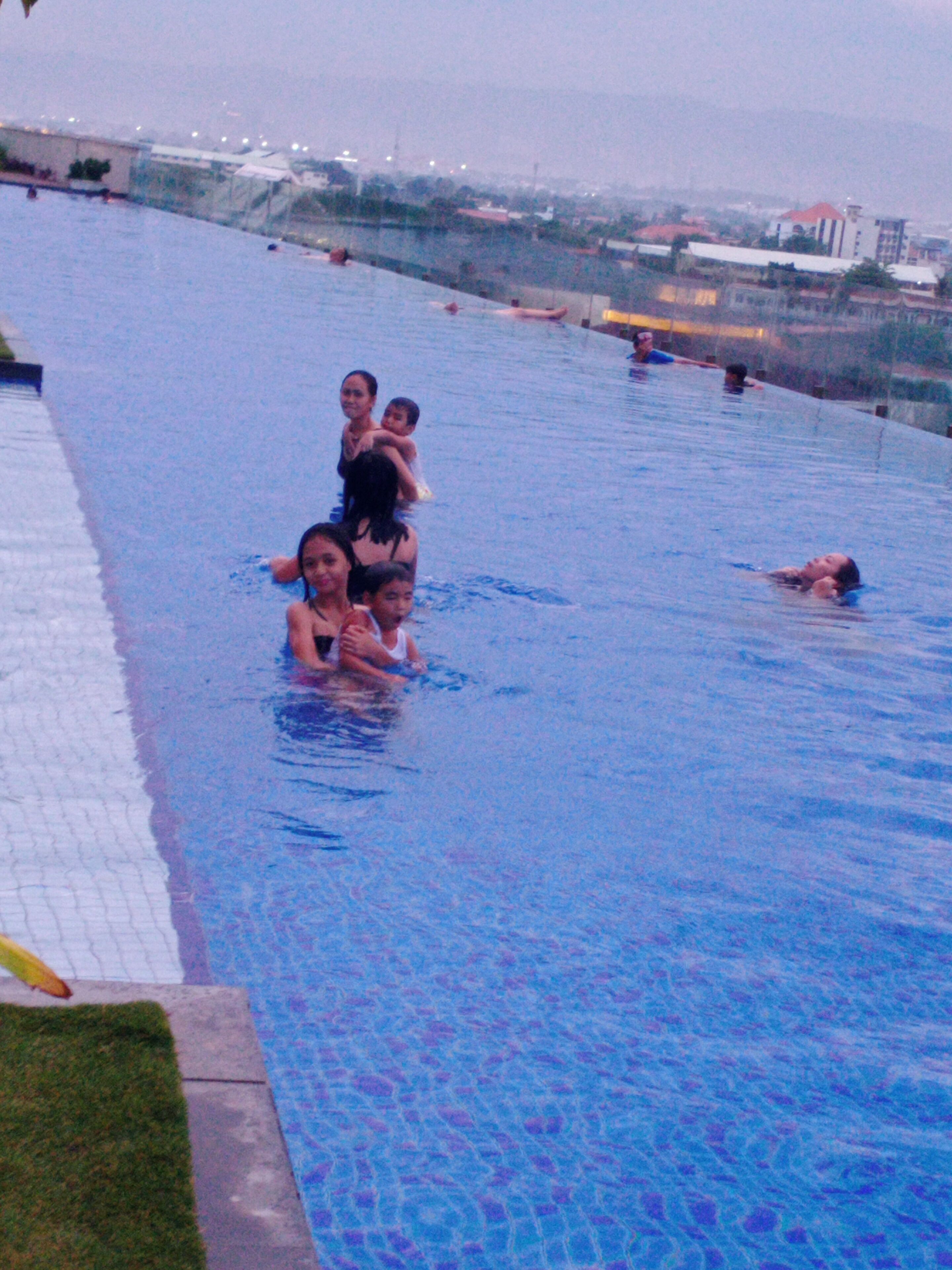 Ein Schwimmbad mit badenden und stehenden Personen.