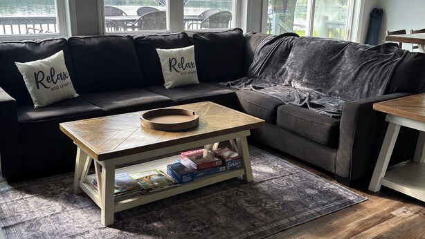 Ein Wohnzimmer mit einer schwarzen Ledersofa, einem Holztisch und einem gemusterten Teppich.