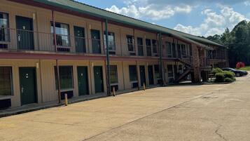 A motel with multiple rooms, a covered parking area, and a staircase leading to an upper level.