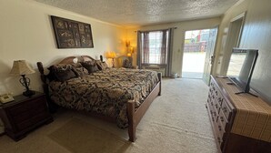A bedroom with a large bed, bedside lamps, a dresser, and a television.