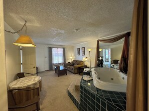 A living room with a sofa, a coffee table, a lamp, and a large window with curtains.