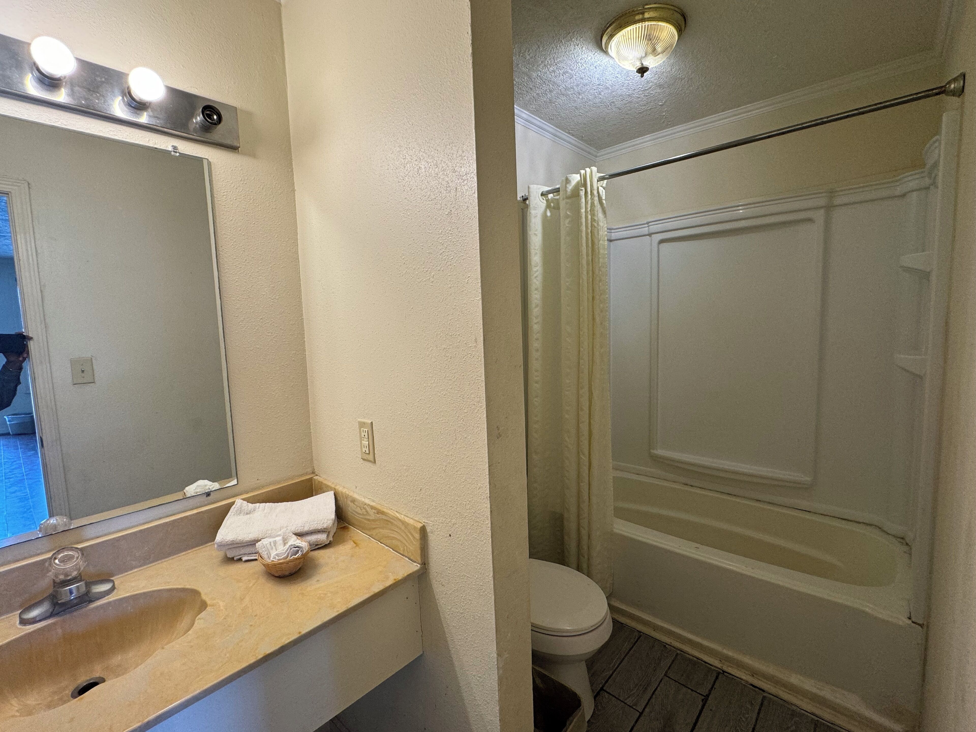 A bathroom with a sink, mirror, and a shower area.
