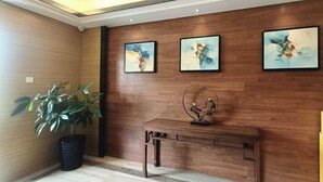 Eine Holzwand mit drei abstrakten Gemälden, einem Blumentopf und einem Schreibtisch mit einem dekorativen Gegenstand.