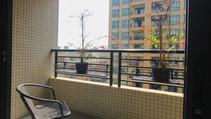 Ein Balkon mit Stuhl und Topfpflanzen, mit Blick auf ein Wohngebäude.