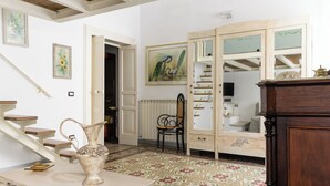 A room with a staircase, a wooden cabinet, a chair, and a table with a vase. - Appartamento Vintage con Balcone by Wonderful Italy (Ostuni)