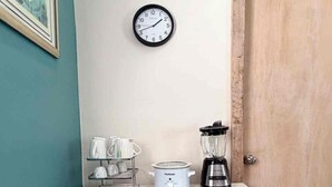 A kitchen area with a white countertop, a coffee maker, a blender, and a clock on the wall. - Waterfront Gulfport Studio w/Shared Private Beach + Walk to Beach & Dining (Gulfport)