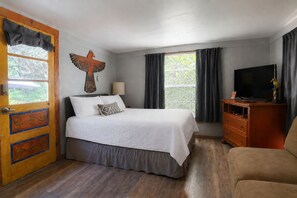 Un dormitorio con cama, televisión, cómoda y ventana con cortinas.