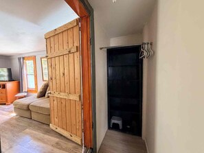Ein Zimmer mit einer Schiebetür aus Holz, einem Sofa, einem Fernseher und einem kleinen Hocker.