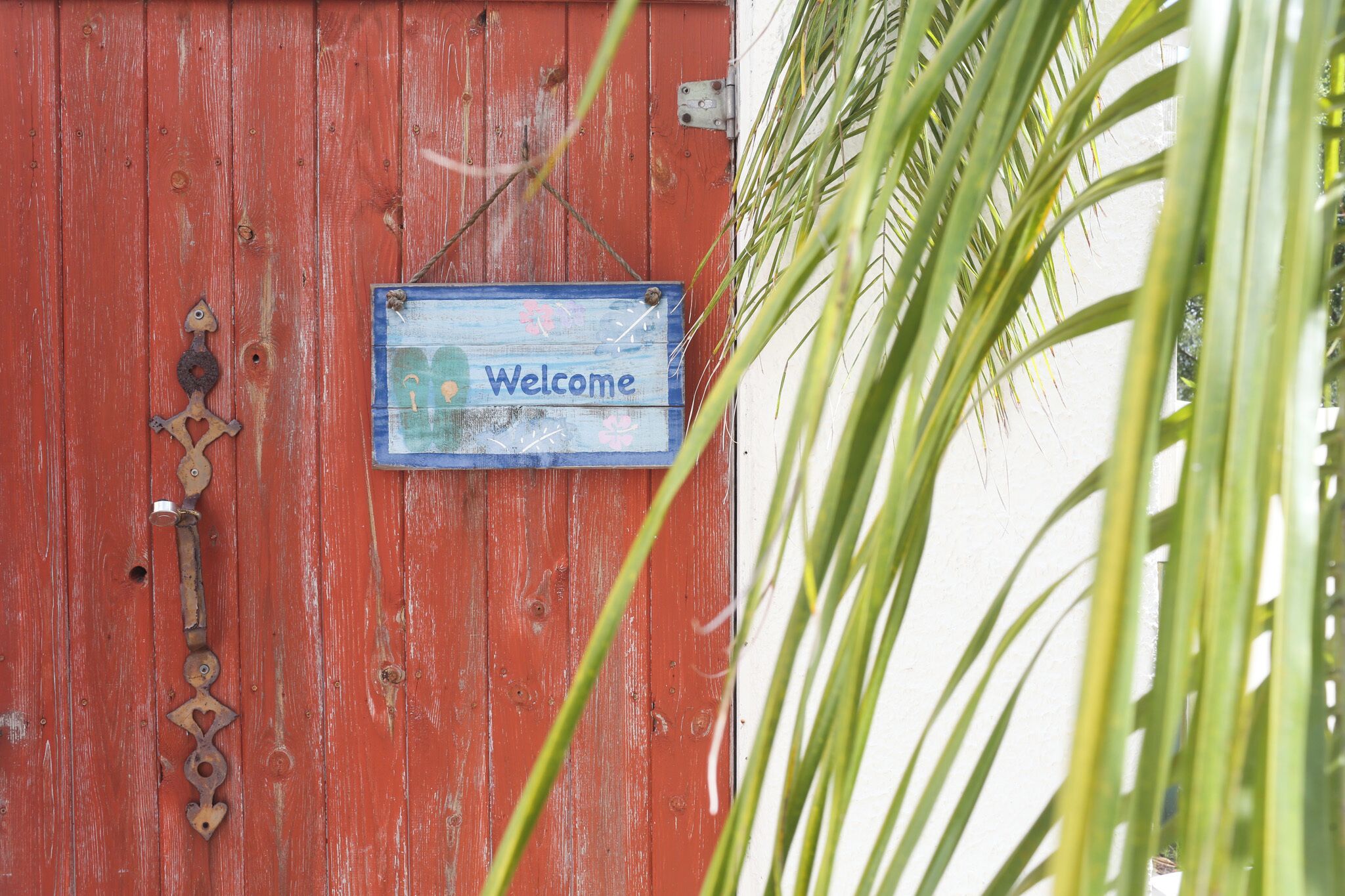 A red wooden door with a 'Welcome' sign and a metal latch.