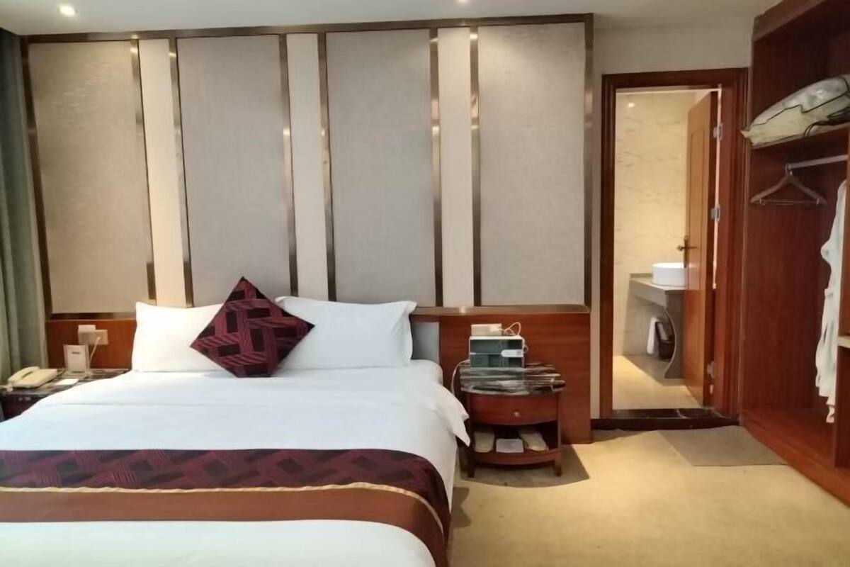 Hotellihuone, jossa on sänky, yöpöytä ja vaatekaappi.