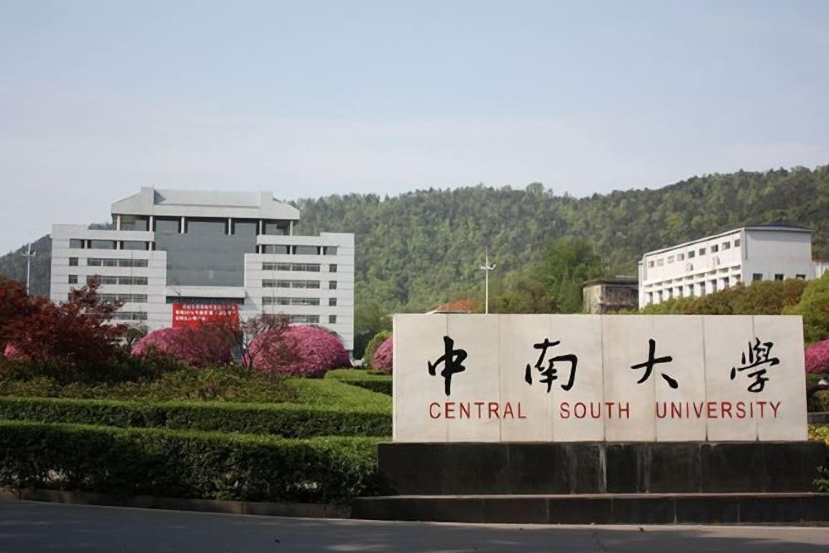 A sign for Central South University with a modern building in the background.