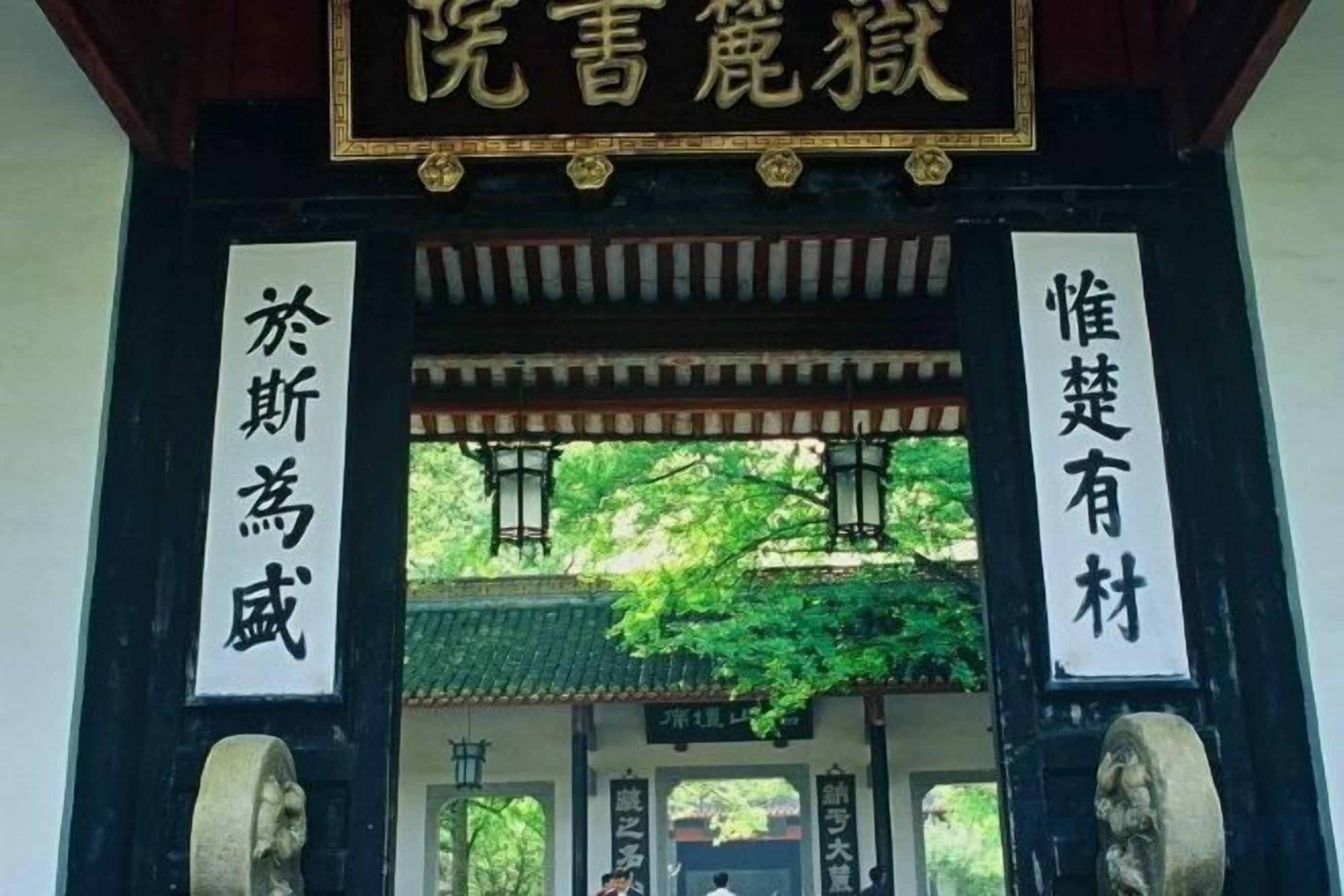 A traditional Chinese gate with inscriptions, a tiled roof, and a stone pillar.