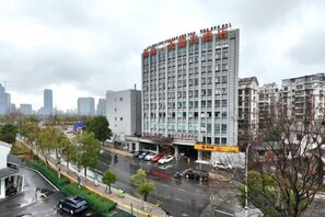 A multi-story building with a commercial ground floor, surrounded by a cityscape and a wet street. - Handsome Tianlu Hotel (Changsha)