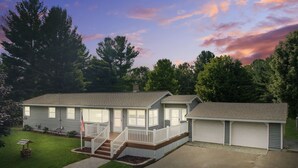 A two-story house with a front porch and a garage. - Summer Home near Long Lake with Hot Tub & Firepit (Traverse City)