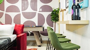 A modern room with a pool table, green chairs, a red sofa, and a wall with geometric patterns. - Arts District Group Suite | Sleeps 10 + Pool Table (Las Vegas)