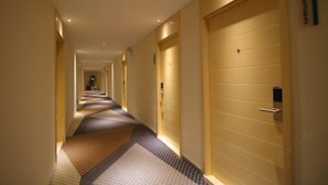 A hotel corridor with multiple doors, a patterned carpet, and recessed lighting. - Tulou·He Hotel (Shanghai Songjiang New City Metro Station Branch) (Shanghai)