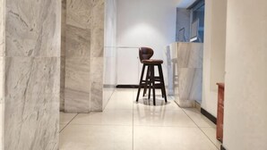 A hallway with marble walls, a chair, and a tiled floor. - Tulou·He Hotel (Shanghai Songjiang New City Metro Station Branch) (Shanghai)