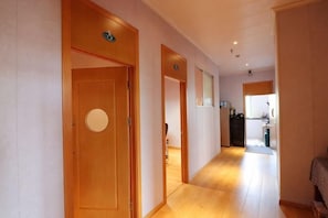 Passadís amb portes de fusta, una cuina al fons i un llum de sostre visible.