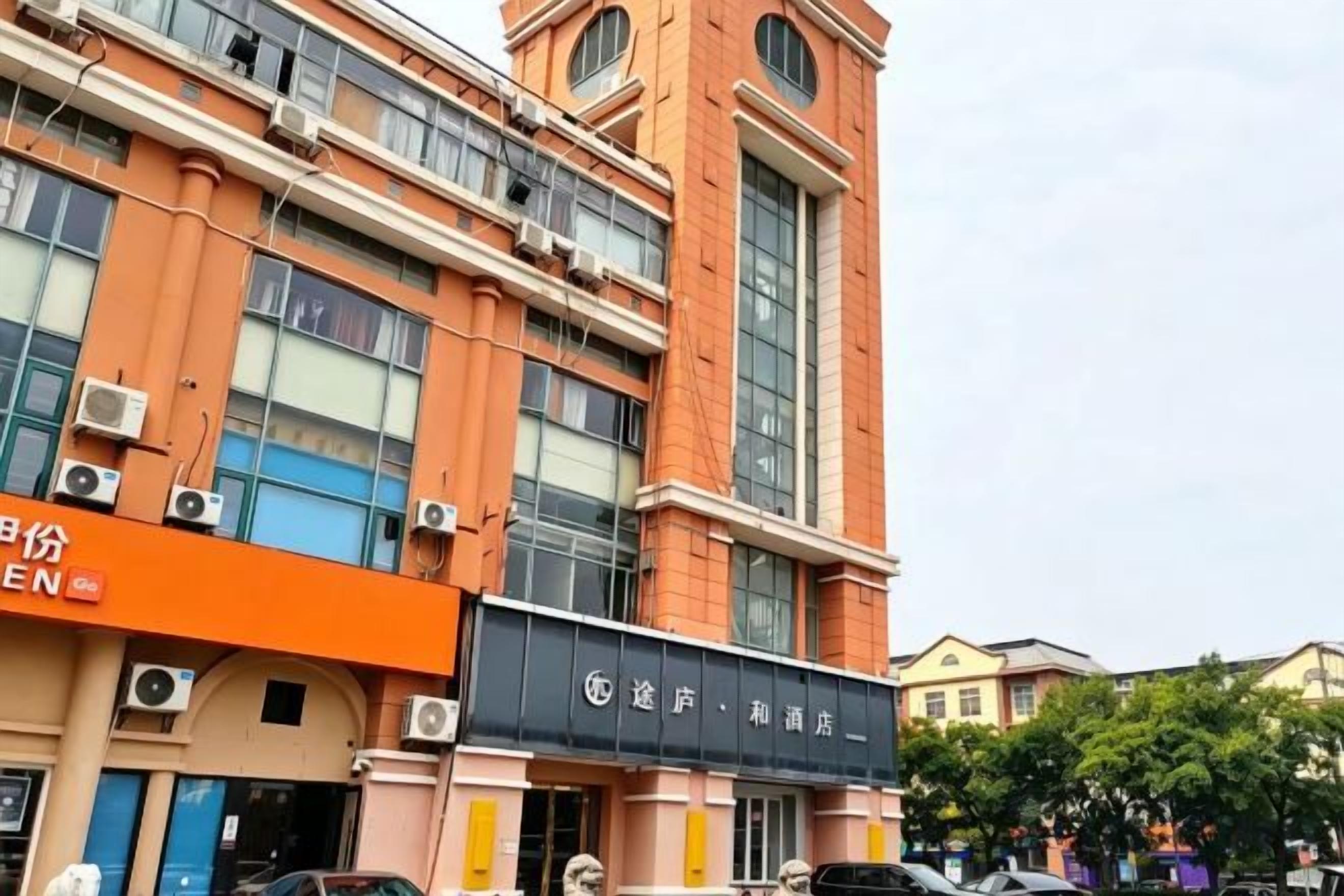 A multi-story building with a prominent orange facade, large windows, and air conditioning units.