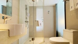 A modern bathroom with a glass-enclosed shower, a white sink, and a toilet. - Tulou·He Hotel (Shanghai Songjiang New City Metro Station Branch) (Shanghai)