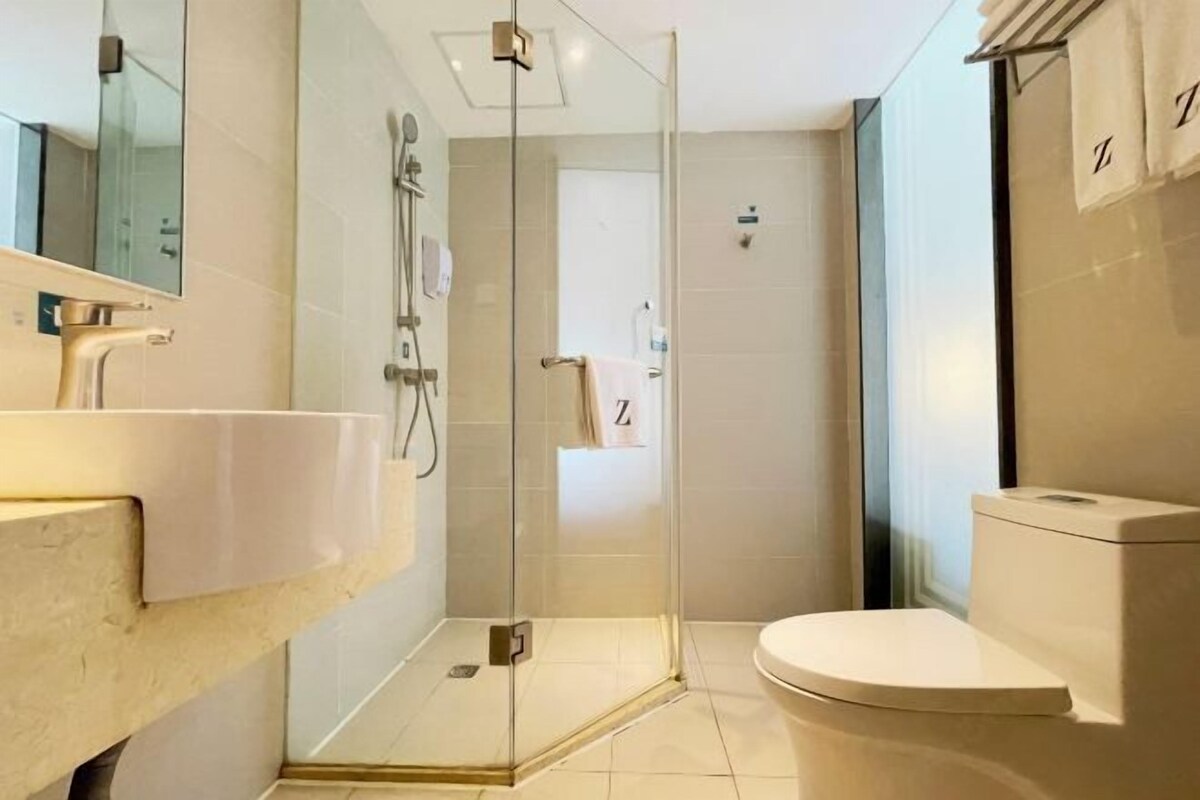 A modern bathroom with a glass-enclosed shower, a white sink, and a toilet.