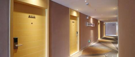 A hotel corridor with doors numbered 8323 and 8324, a tiled floor, and a ceiling with recessed lighting.