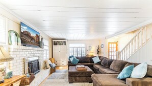 A cozy living room with a fireplace, a sectional sofa, and a large window.