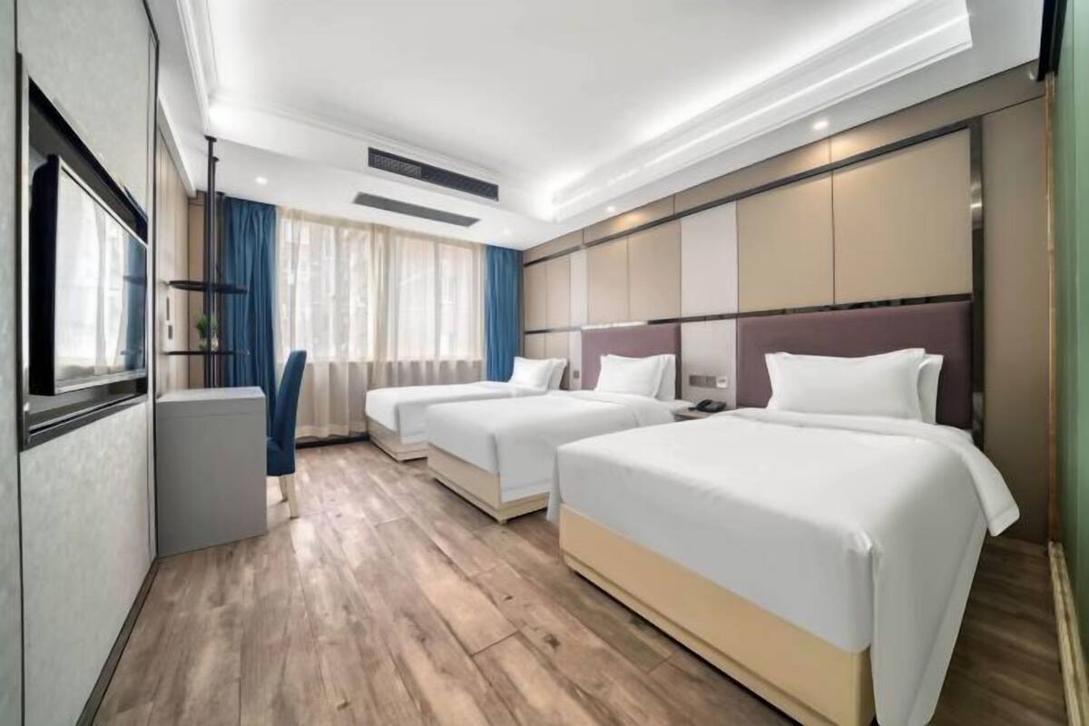 A hotel room with two beds, a desk, and a window with curtains.