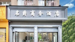 A hotel entrance with a modern design, featuring a prominent sign above the doors and a glass facade. - Mingjue Business Hotel (Wenling)