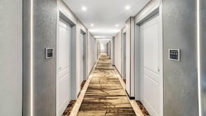 A long, narrow hotel corridor with white doors on either side, a patterned carpet, and a ceiling with recessed lighting. - Mingjue Business Hotel (Wenling)